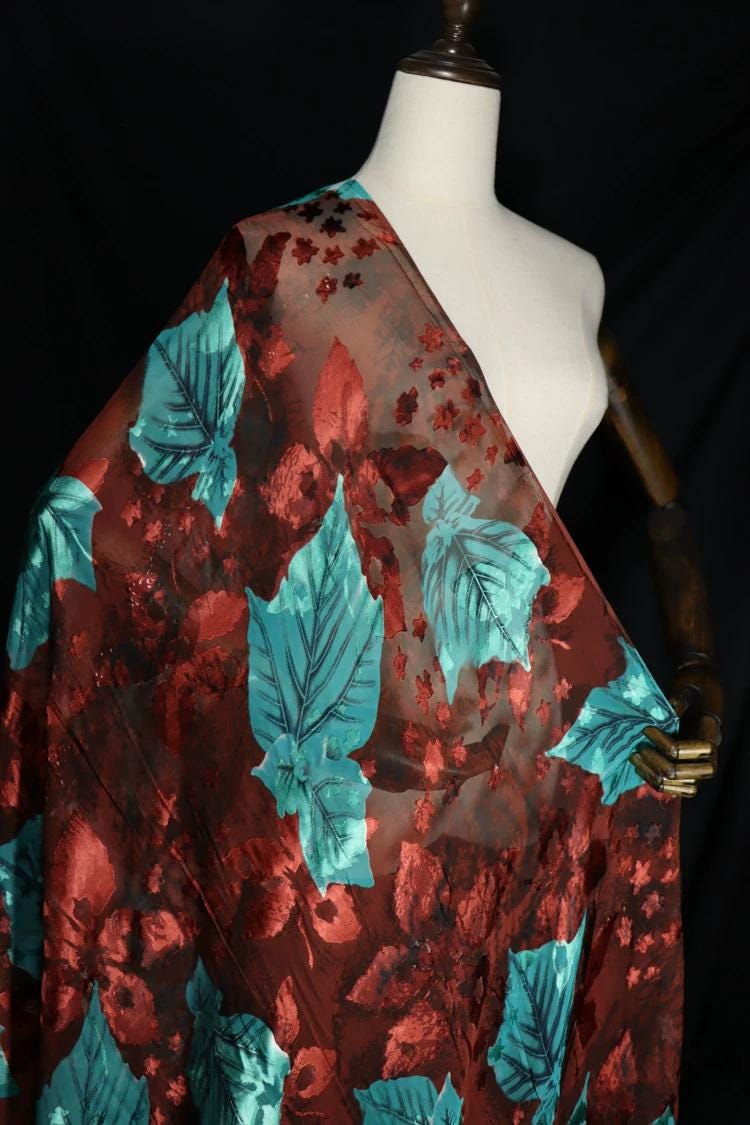 A mannequin wearing a red and green floral fabric draped over it.