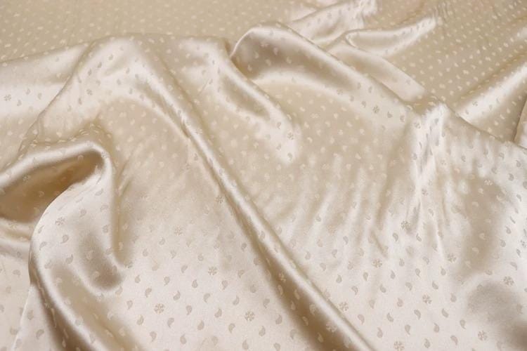 a close-up view of a crumpled, light-colored fabric with a pattern of small white dots or circles on it.