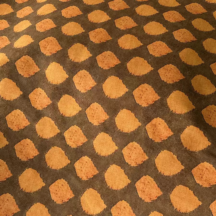 a close-up view of a fabric with a repeating pattern of orange and brown circles or shapes, creating a visually striking and textured design.