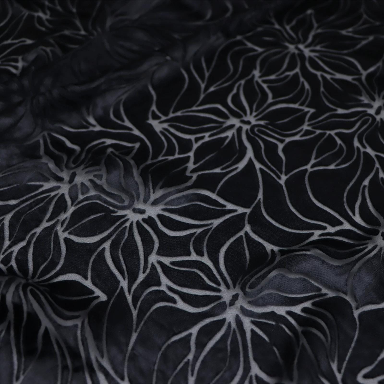 a close-up view of a fabric with a repeating floral pattern in black and white.