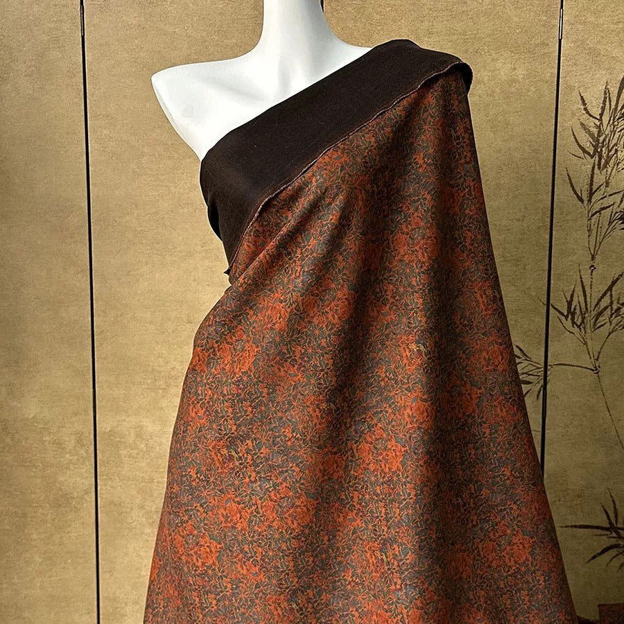 A mannequin wearing a brown and orange patterned fabric draped over its body.