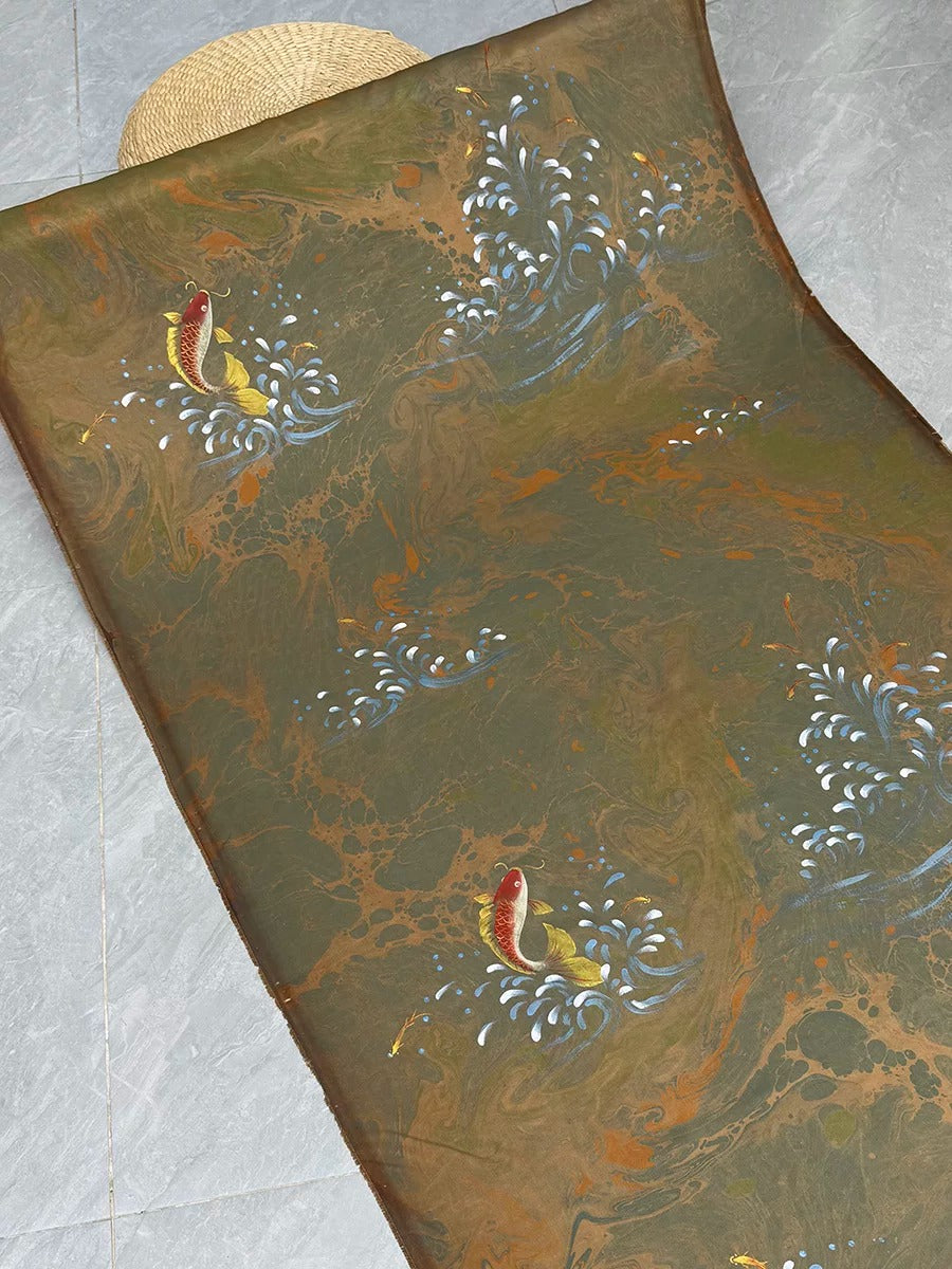 a piece of fabric with a marbled pattern, including a fish design. The fabric appears to be a piece of art or a decorative textile.