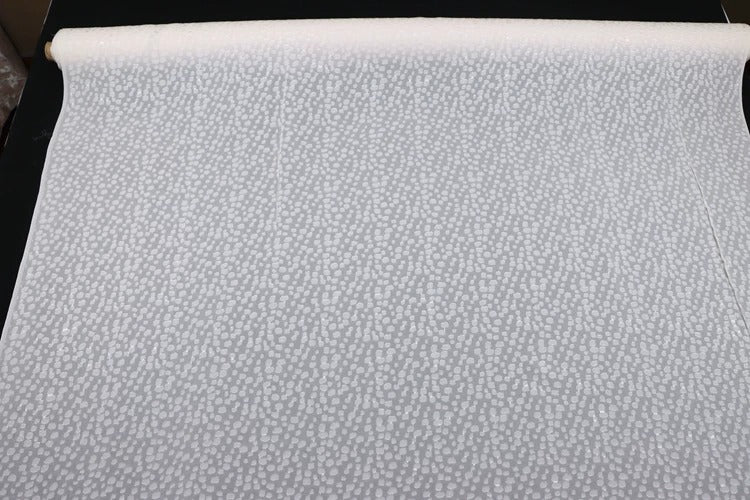 a roll of white fabric with a pattern of small white dots or circles on it.