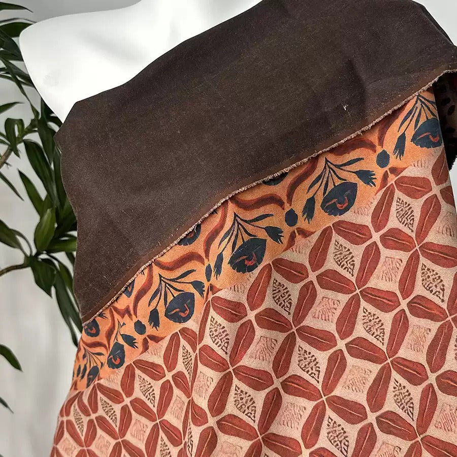 a mannequin wearing a brown and orange patterned dress with a floral design.