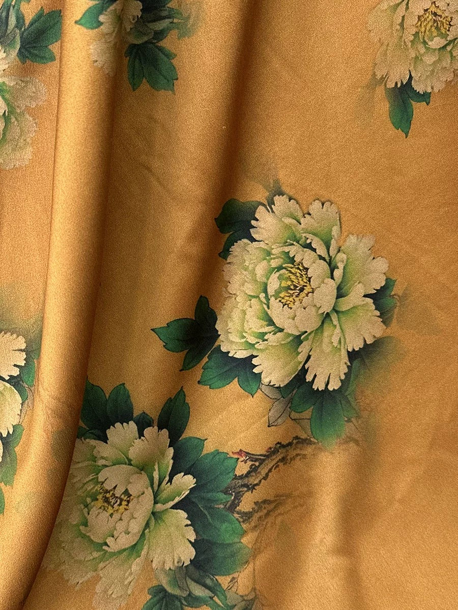 a close-up view of a fabric with a floral pattern, including white and green flowers and leaves. The fabric appears to be a light brown color, and the pattern is intricate and detailed.