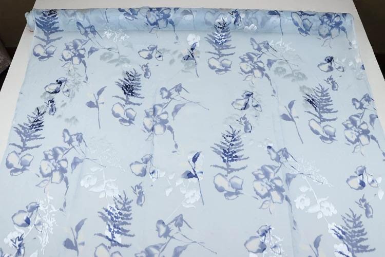 a fabric with a repeating pattern of blue and white floral designs.