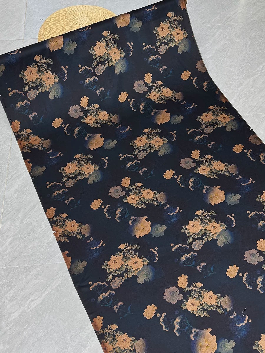 a dark blue fabric with a floral pattern, including various shades of orange and yellow flowers. The fabric appears to be rolled up and placed on a surface, possibly a table or countertop.