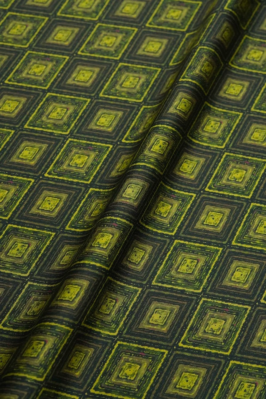 a close-up view of a fabric with a repeating pattern of green and black squares. The pattern is composed of small squares arranged in a diagonal grid-like design, creating a visually striking and intricate pattern.