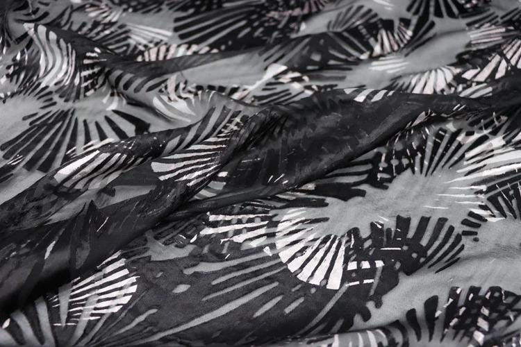a close-up view of a fabric with a black and white abstract pattern, featuring a repeating design of black and white lines and shapes.