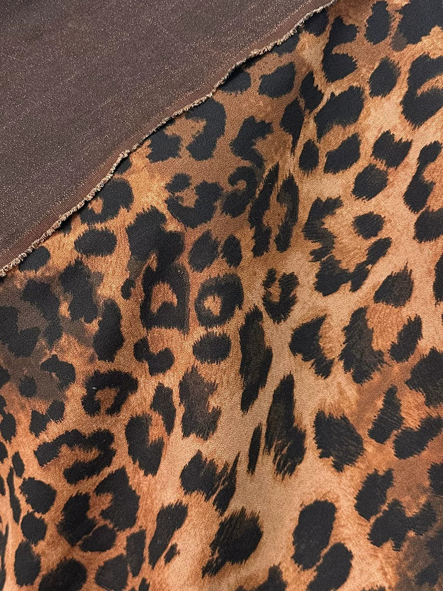 a close-up view of a fabric with a leopard print pattern, featuring a mix of brown and black spots.