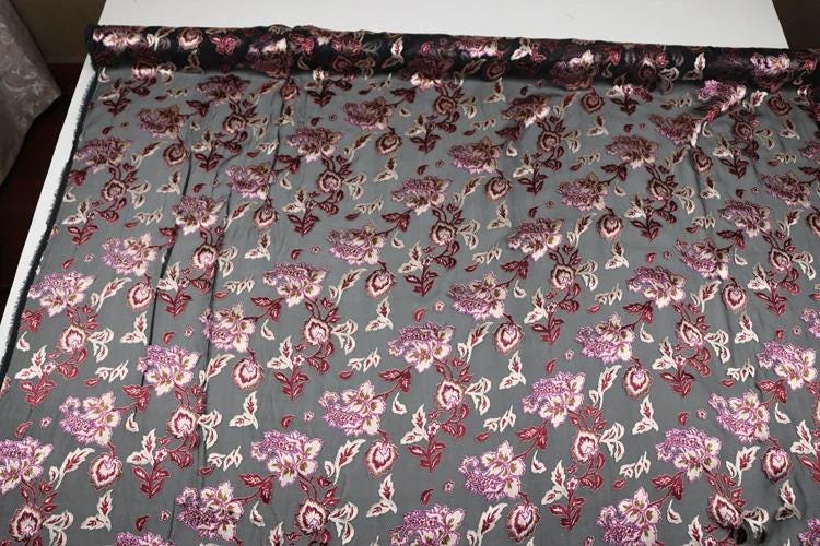a fabric with a floral pattern in shades of gray and red, featuring a repeating design of pink and white flowers.