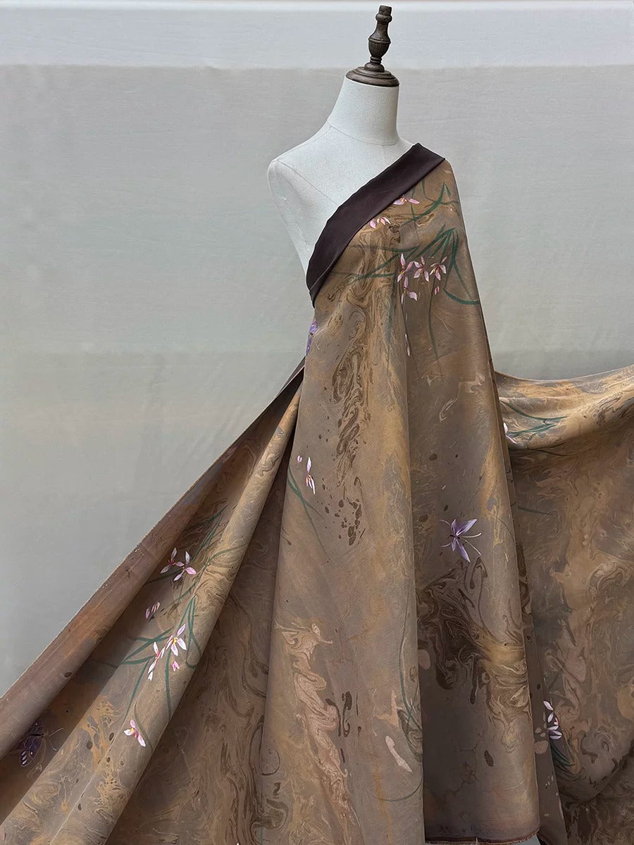 A mannequin wearing a long, flowing dress with a floral pattern in shades of brown and gold.