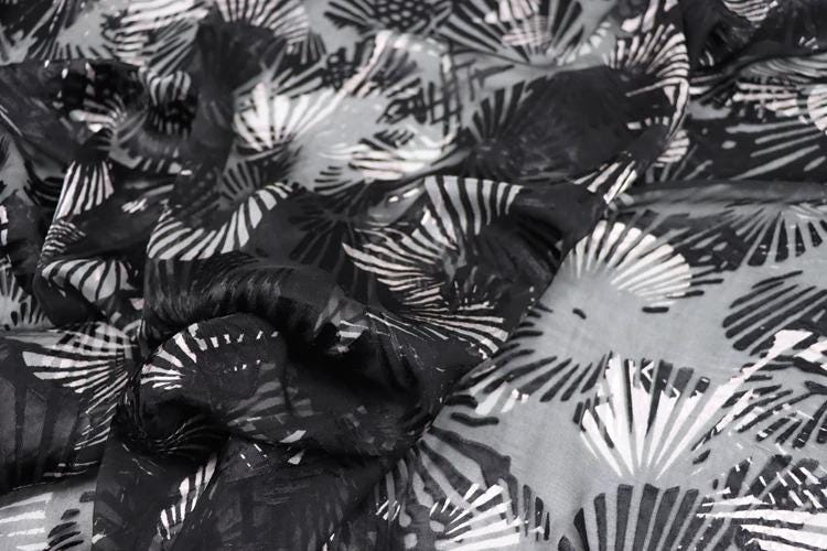 a close-up view of a fabric with a black and white pattern of overlapping shells or leaves.