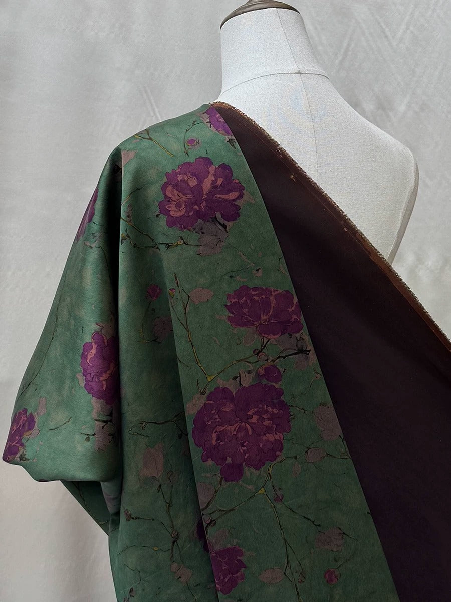 A mannequin wearing a green and purple floral print dress with a brown shawl draped over it.