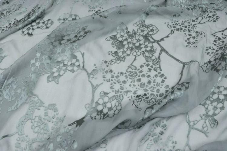 a close-up view of a fabric with a floral pattern, featuring a mix of gray and white colors.