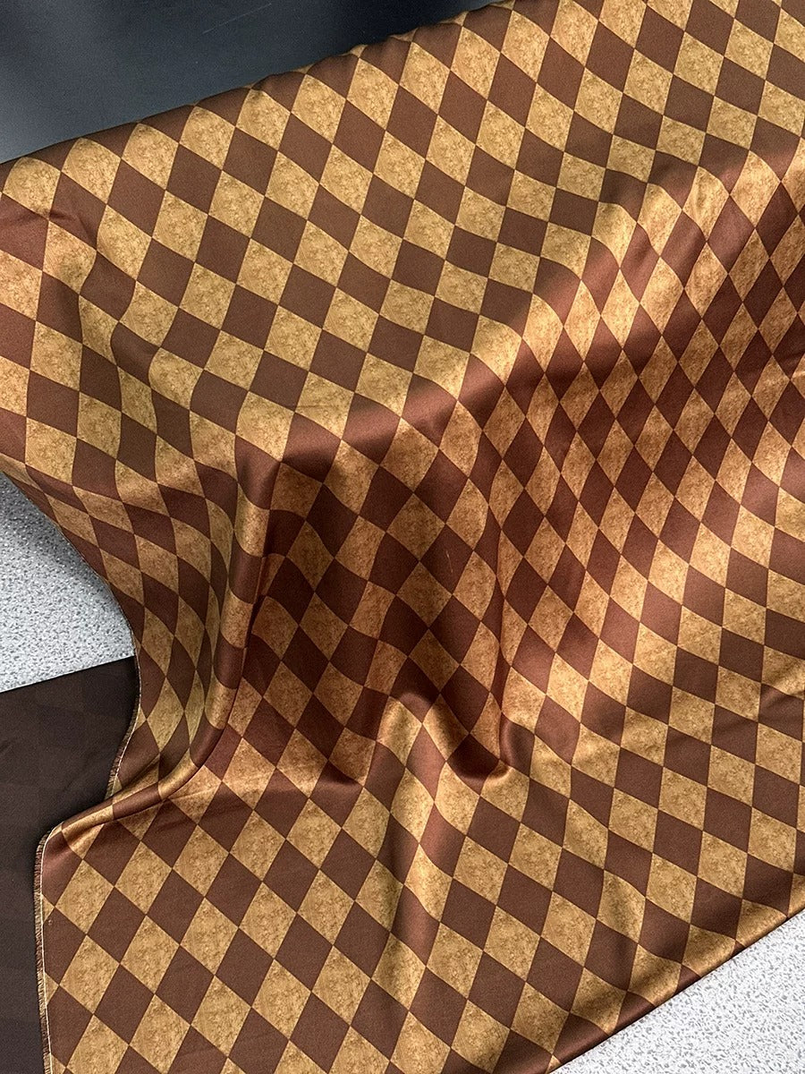 a close-up view of a fabric with a checkered pattern in shades of brown and gold. The fabric appears to be folded or crumpled, giving it a textured and wrinkled appearance.
