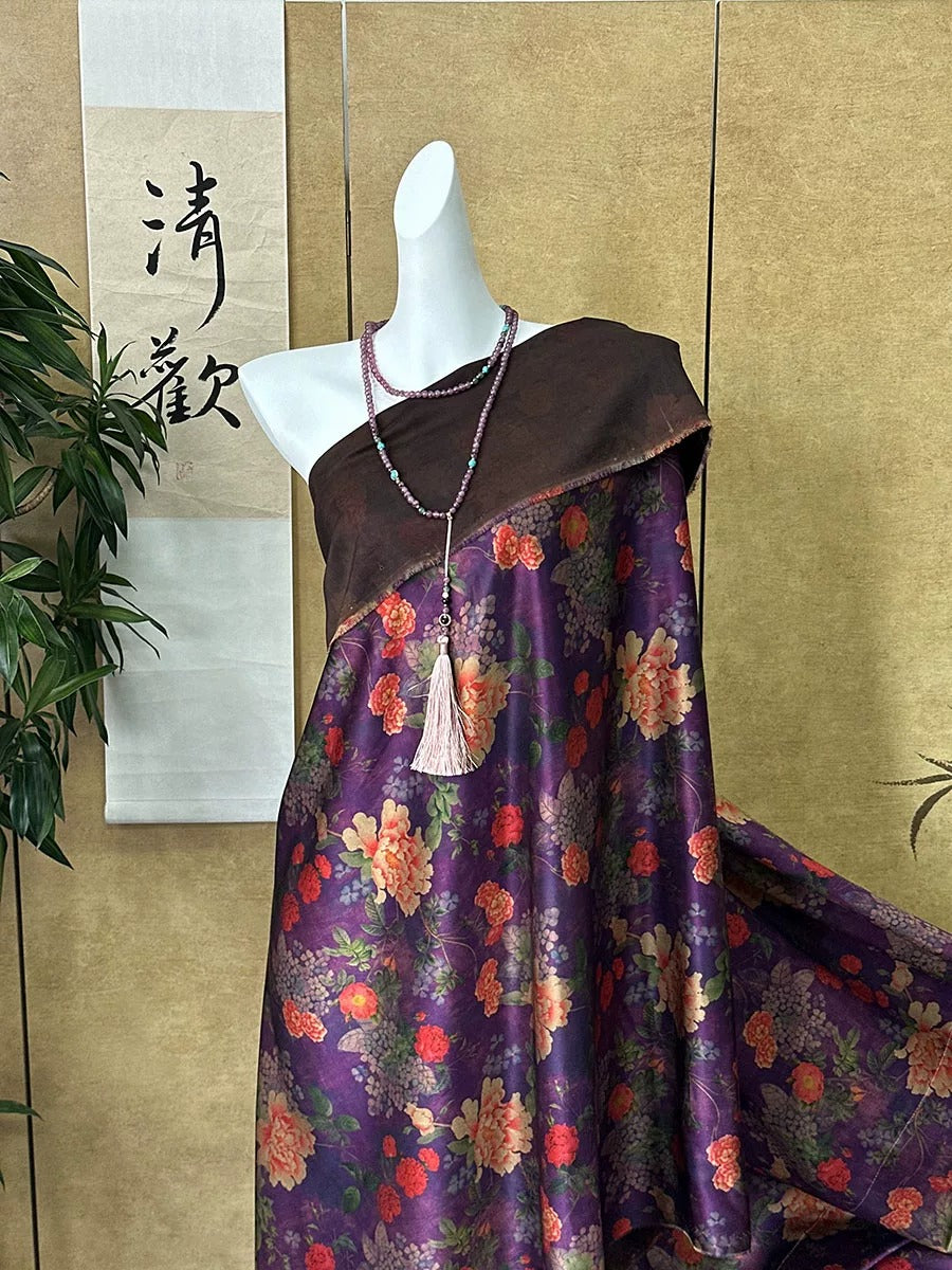 A mannequin wearing a purple floral dress with a brown shawl draped over it, displayed in a room with a plant and a sign with Chinese characters.