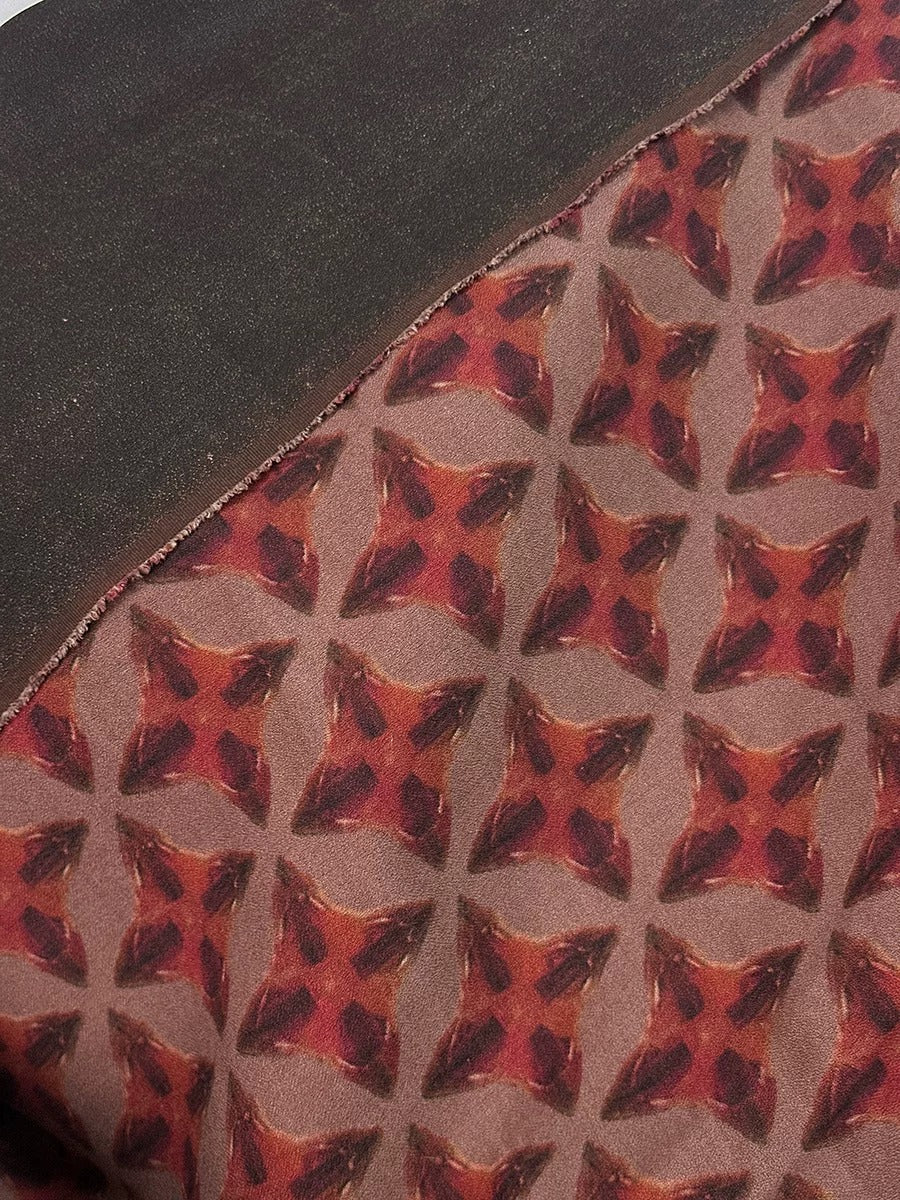 a close-up view of a fabric with a repeating pattern of red and brown geometric shapes, creating a visually striking and intricate design.