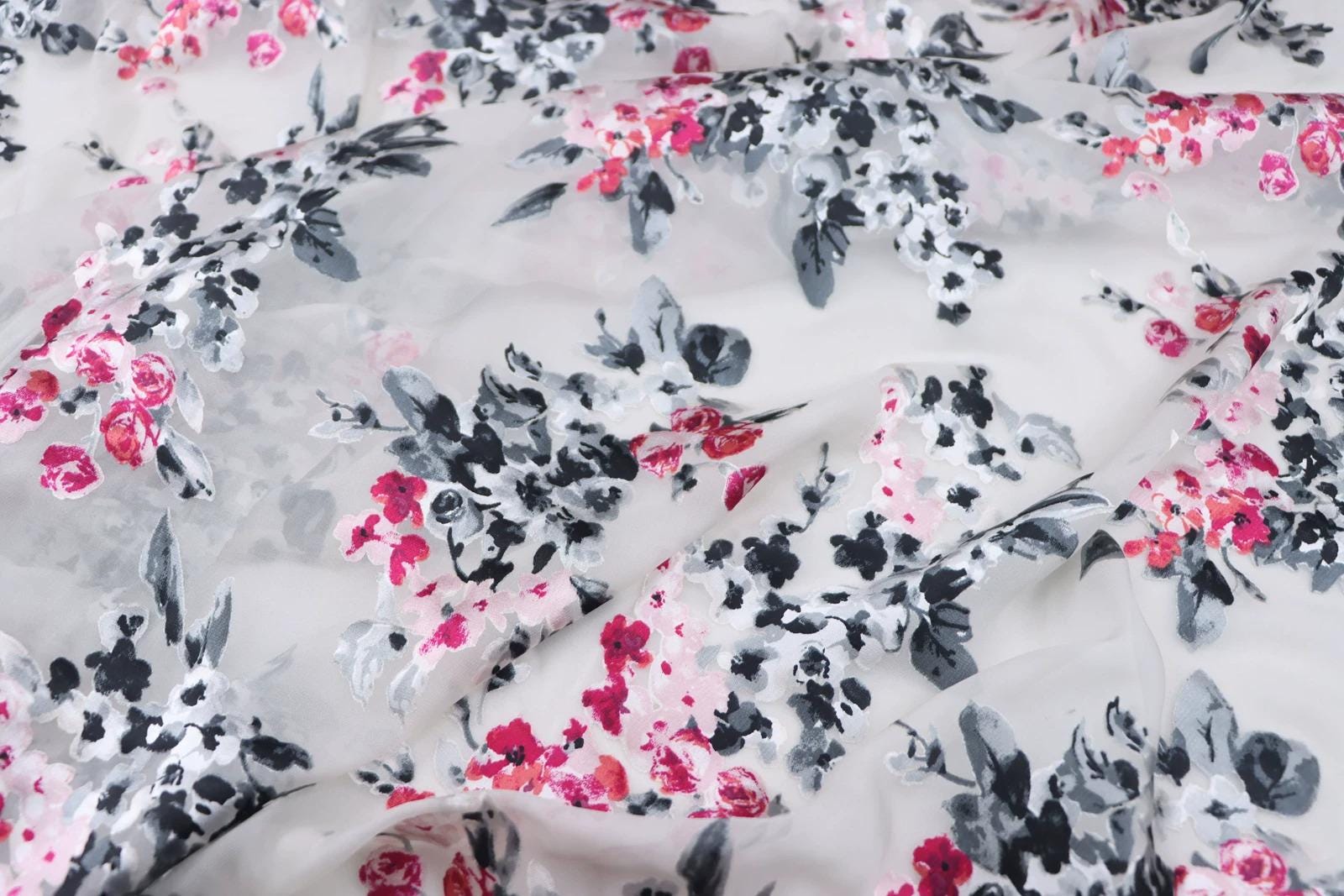 a close-up view of a fabric with a floral pattern in shades of pink, black, and white.