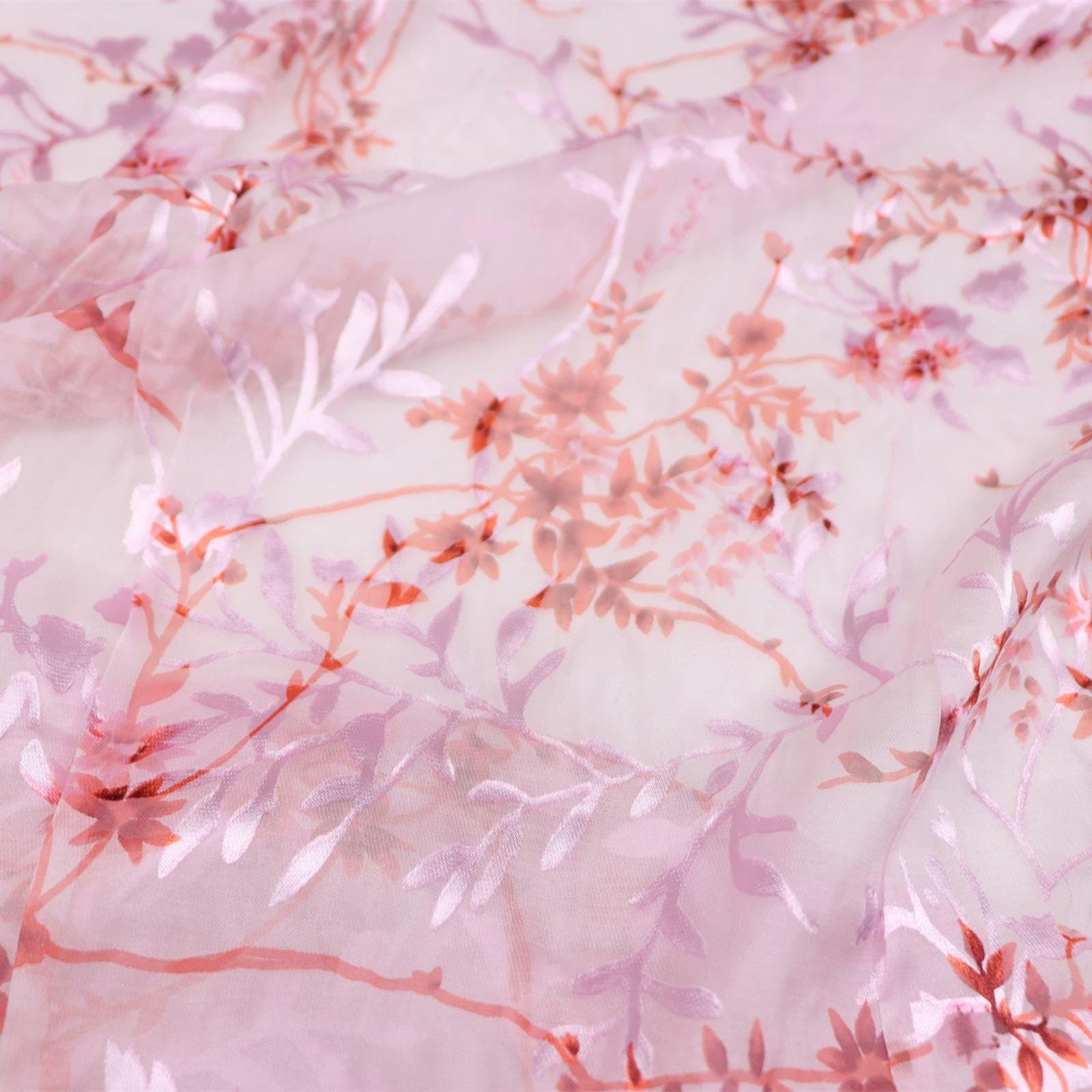a close-up view of a fabric with a pink and red floral pattern. The fabric appears to be made of sheer material, giving it a delicate and airy appearance. The pattern consists of various shades of pink and red flowers and leaves, creating a visually appealing and intricate design.