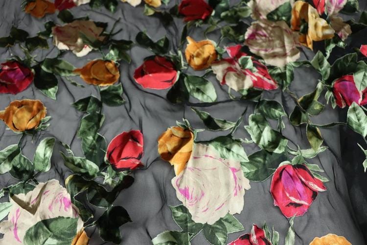 a close-up view of a fabric with a floral pattern, including various colored flowers such as red, orange, and pink, along with green leaves.